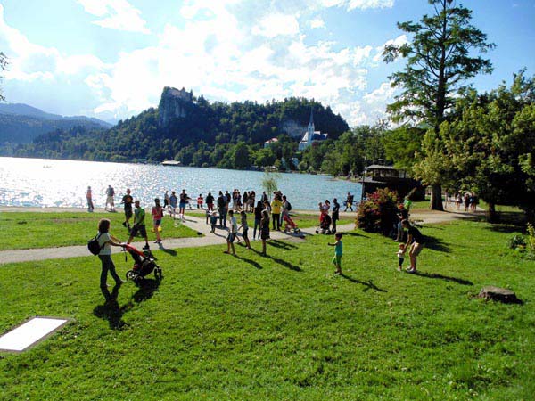 Een foto van het park van Bled en het meer van Bled met in de verte het Kasteel van Bled en de Sint-Martinuskerk